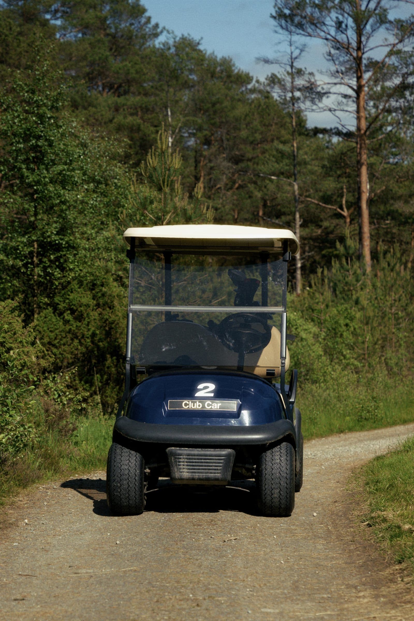 Golfbil på grusstien gjennom skogen på Haugaland Golfbane Sveio
